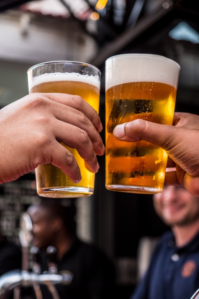 Deux personnes tenant des verres remplis de bière. 