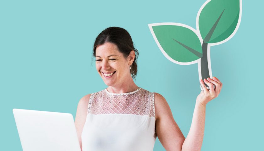 Femme tenant un dessin de plante et un ordinateur